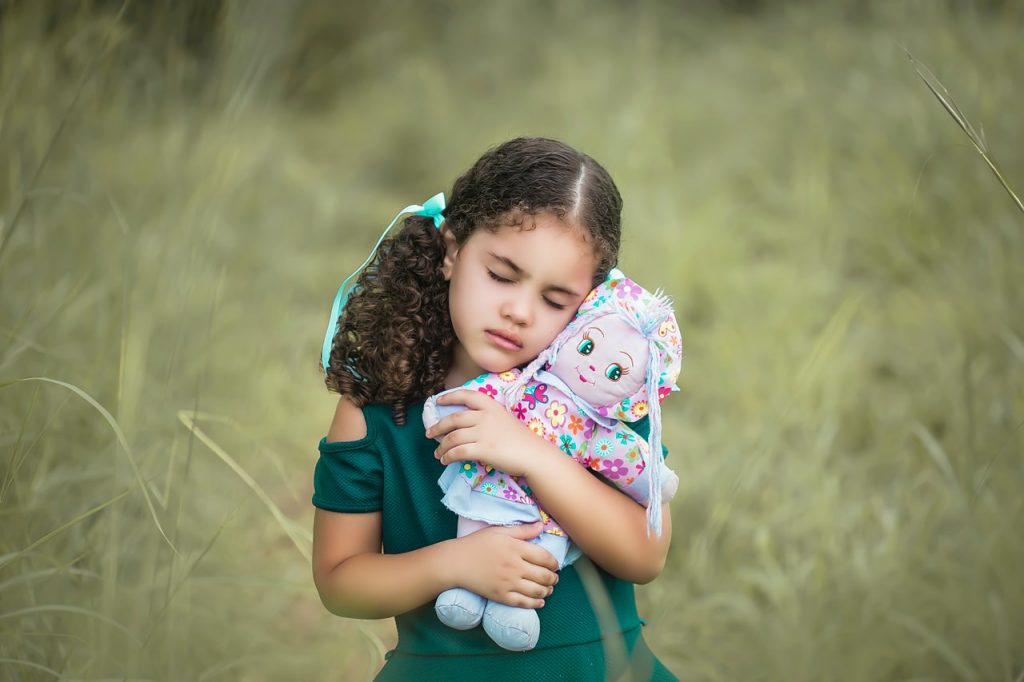 petite fille qui serre sa poupée dans ses bras