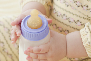 Bébé qui tient un biberon