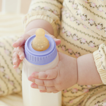 Bébé qui tient un biberon