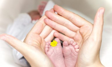 Maman qui tient les pieds de son bébé entre ses mains