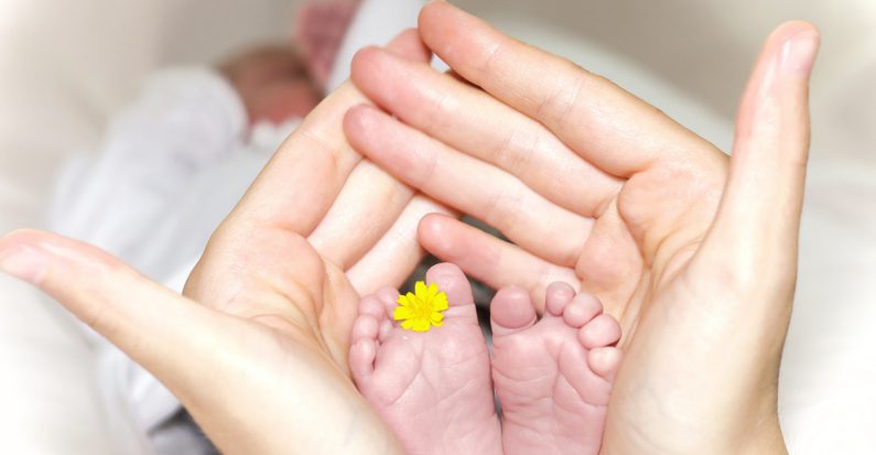 Maman qui tient les pieds de son bébé entre ses mains