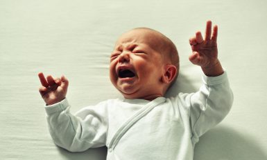 Un bébé sur un lit blanc qui pleure